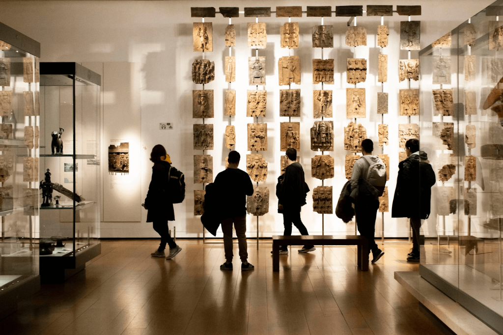 British Museum visitors view a display of Benin Bronzes. Image by Lauren Fleishman for The New York Times.